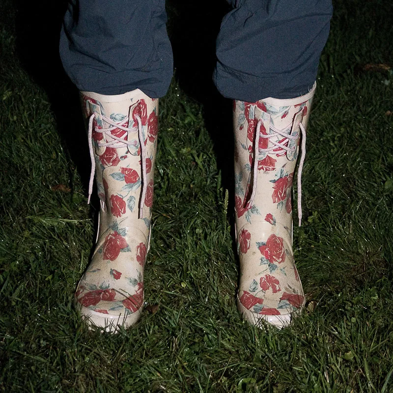 Gummistiefel mit Rosenmuster auf nassem Gras