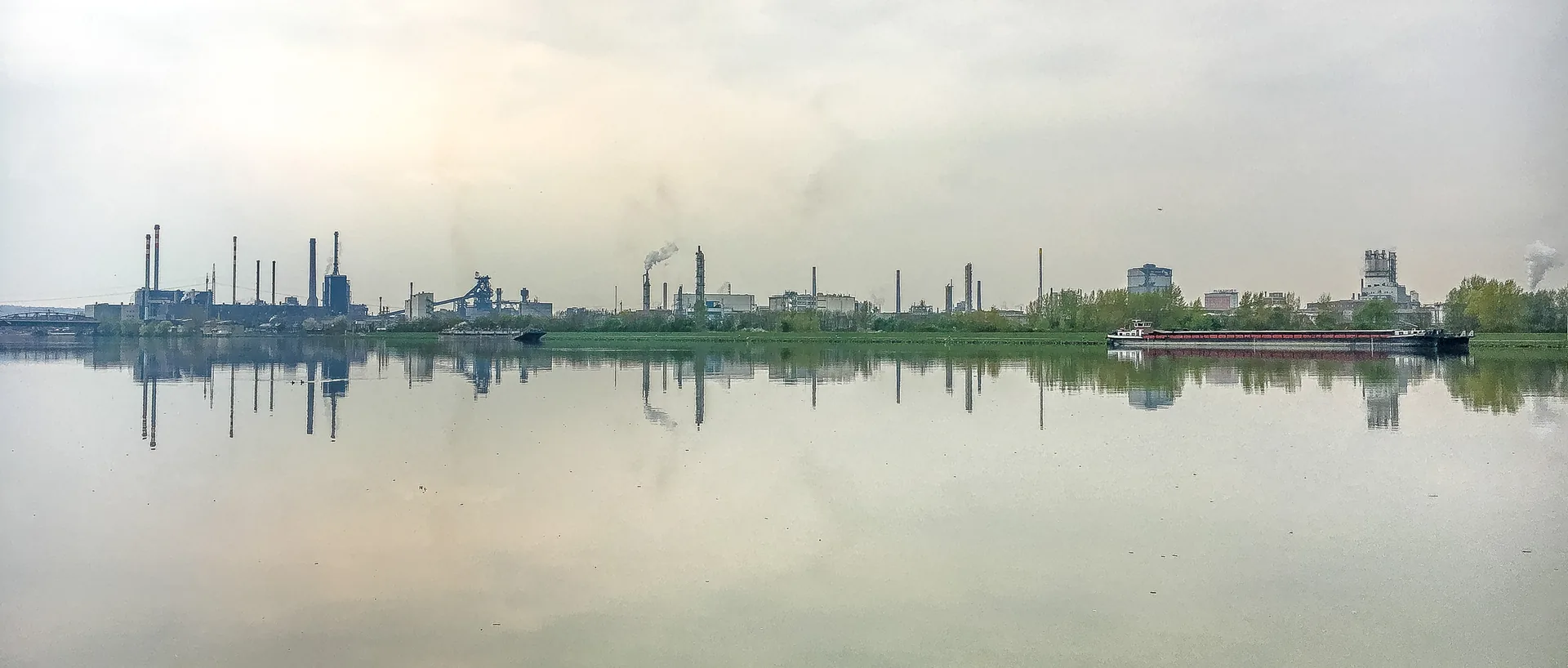 Industriesilhouette am Wasser, im Nebel gespiegelt