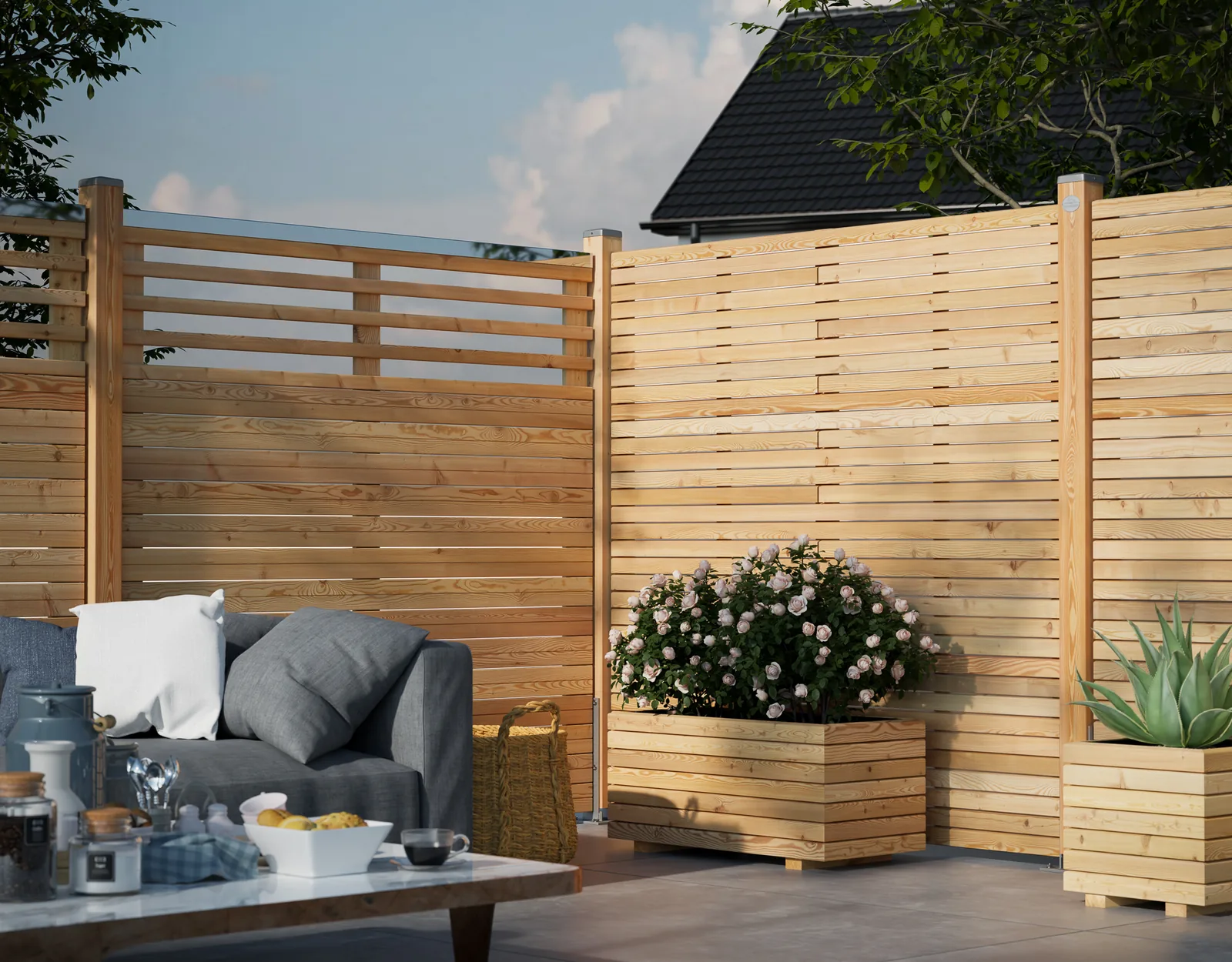 Terrasse mit Sichtschutzzaun aus Holz, grauem Sofa und Blumenkübeln