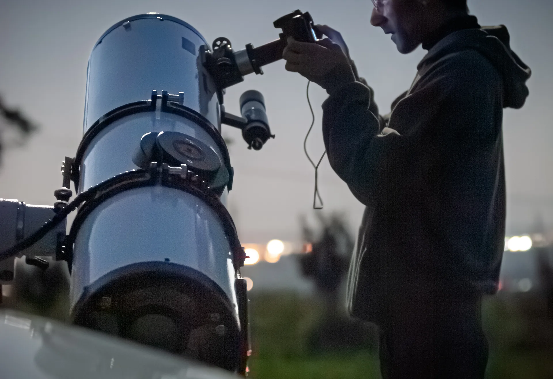 Person mit Kamera an einem Teleskop in der Abenddämmerung