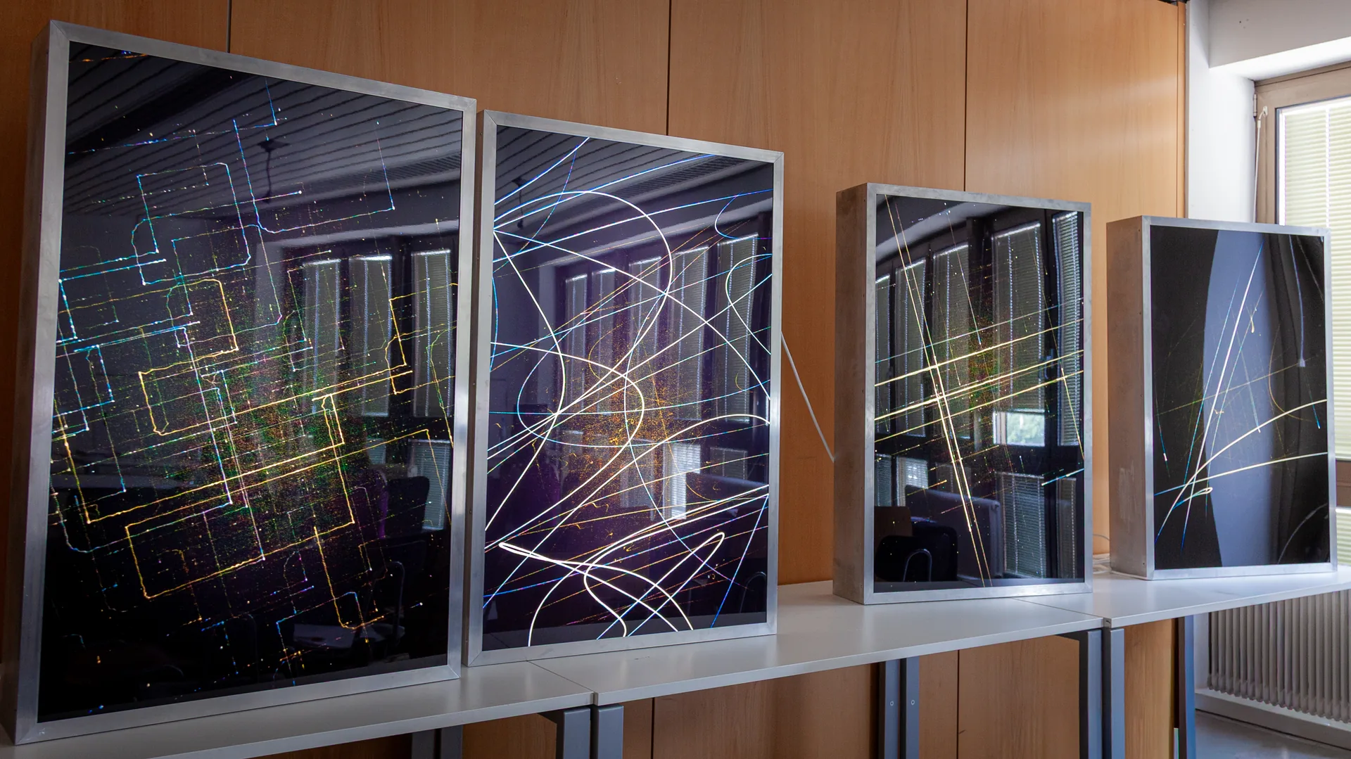 Drei Leuchtkästen 120 x 80 mit Lichtspuren-Motiven auf einem Regal