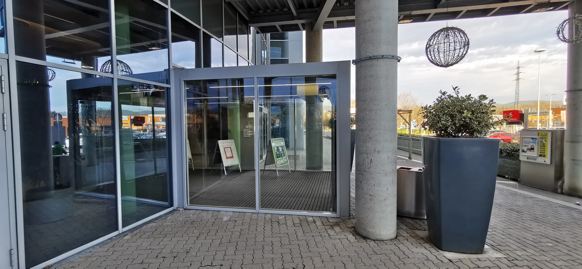 Foto eines Gebäudeeingangs mit Glastüren und Pflanzkübeln, Ausgangsbild